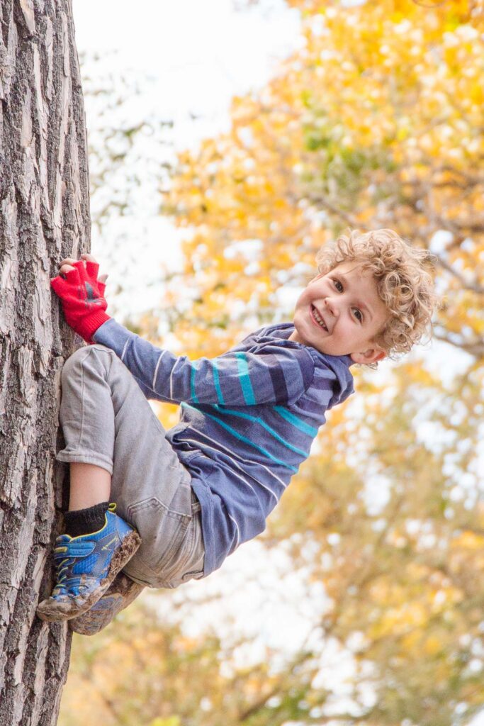 A boy dressed up as a superhero climbs a tree during a creative photoshoot in Albuquerque, New Mexico
